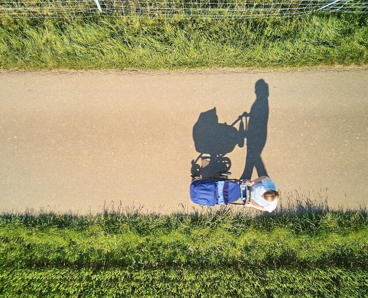 man in black jacket and blue denim jeans sitting on gray concrete road during daytime