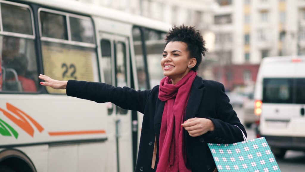 Woman hailing a bus with shopping bags